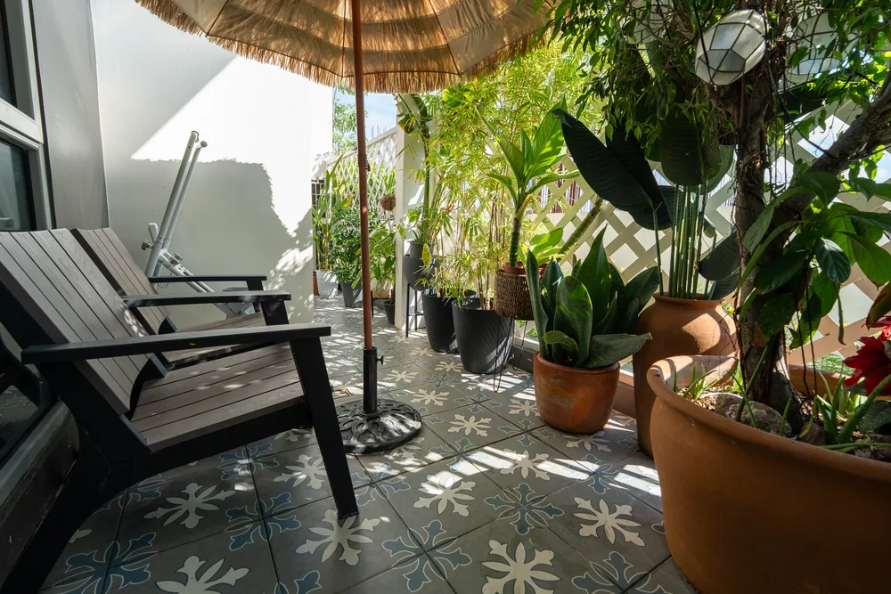 A leafy balcony with patterned tiles and outdoor seating